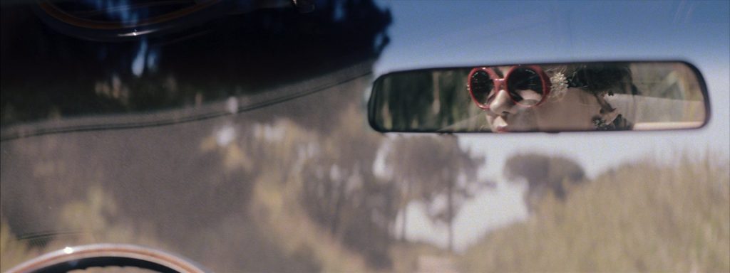 Sweet Matitos fashion film still: red sunglasses reflected in the rear-view mirror
