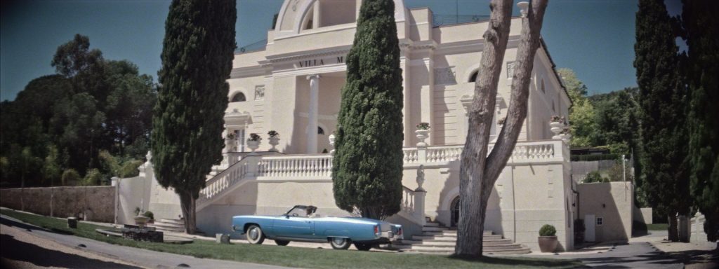 Sweet Matitos fashion film still: a white mansion with a blue convertible parked in front