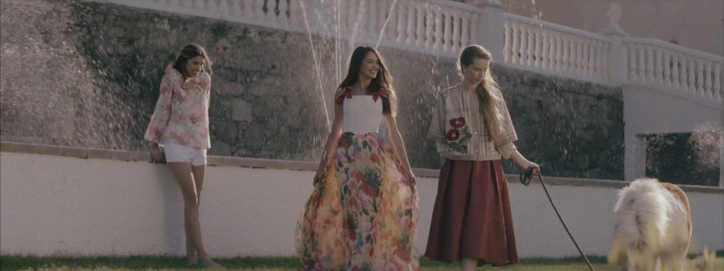 Sweet Matitos fashion film still: three models with a pony in the garden