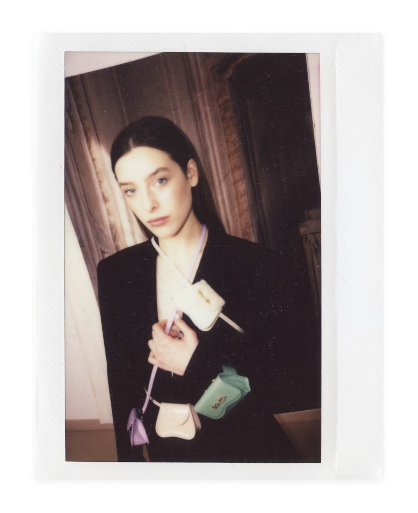 Blame Lilac Poderío: Instax of the model in a black suit with small green and cream bags