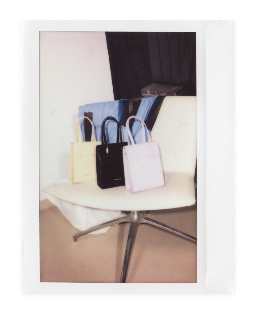 Blame Lilac Poderío: Instax of three bags, cream, black and lilac, on a white chair