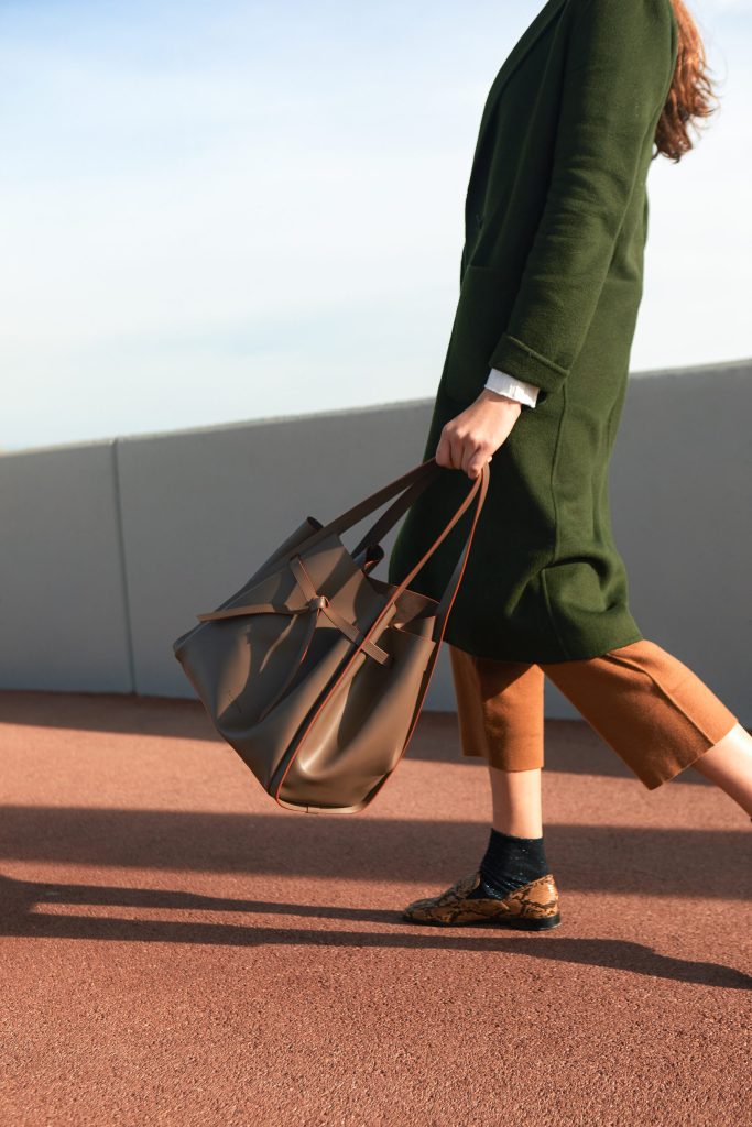 Boria&Coria: model in a green coat walking with a brown bag