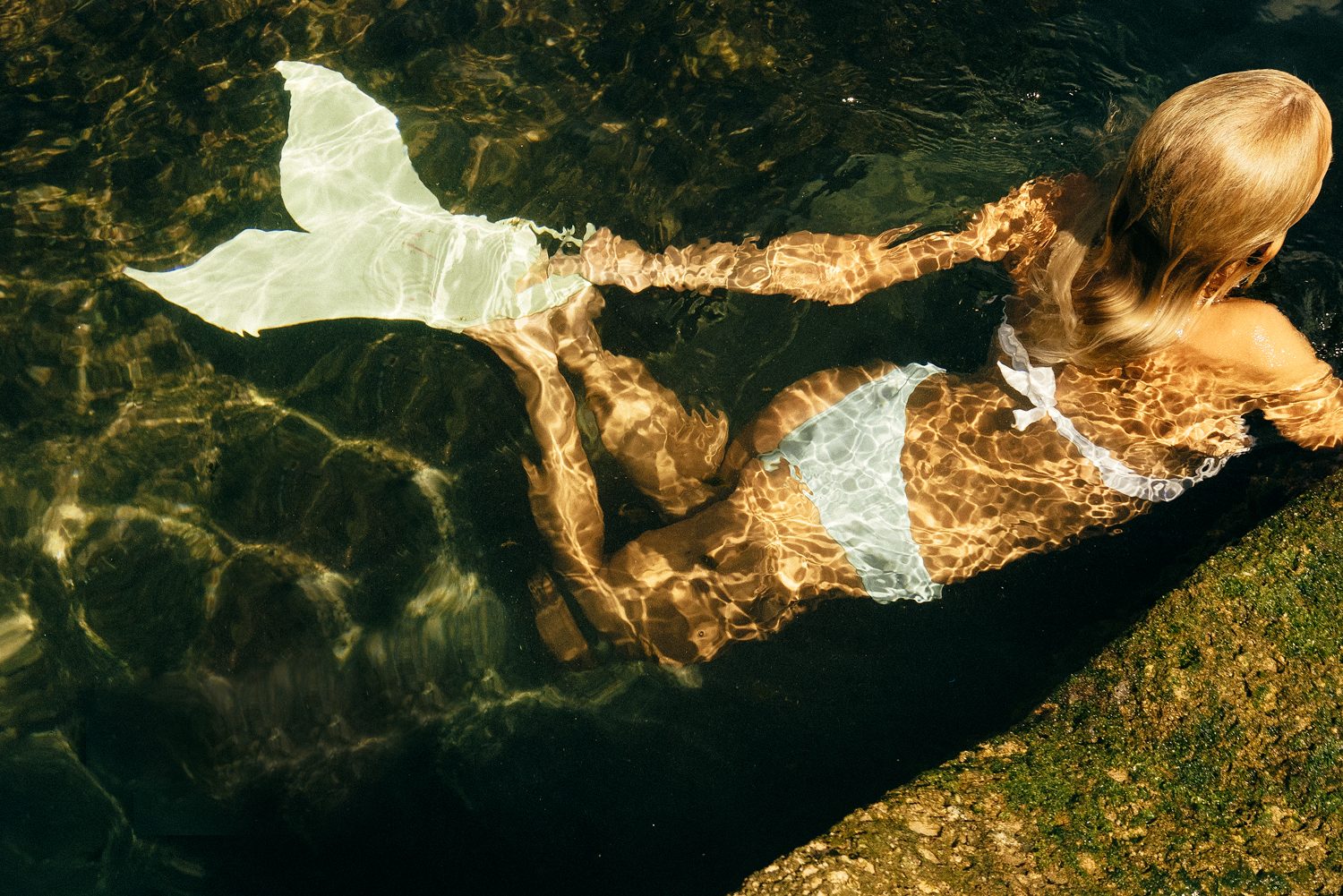 Grain Supply: model with a mermaid tail lying in the water