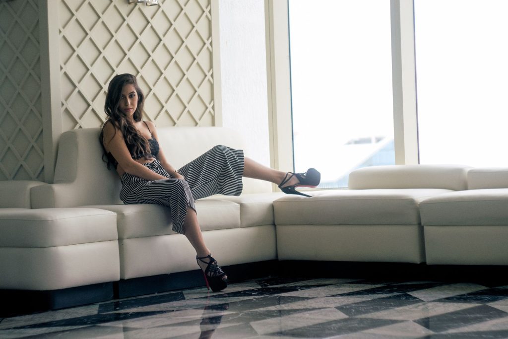 Marcelle sitting on a white sofa in heels