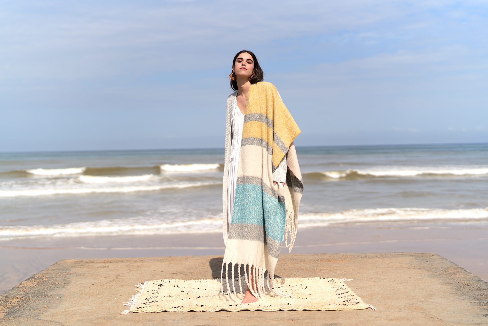 marwa: model in a striped poncho at the water's edge
